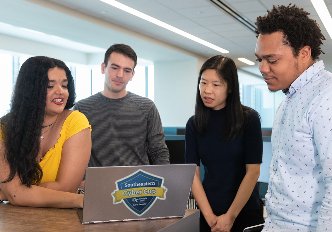 Four students viewing laptop